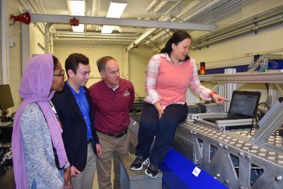 students and faculty look at computer screen in a lab as part of a research collaboration 